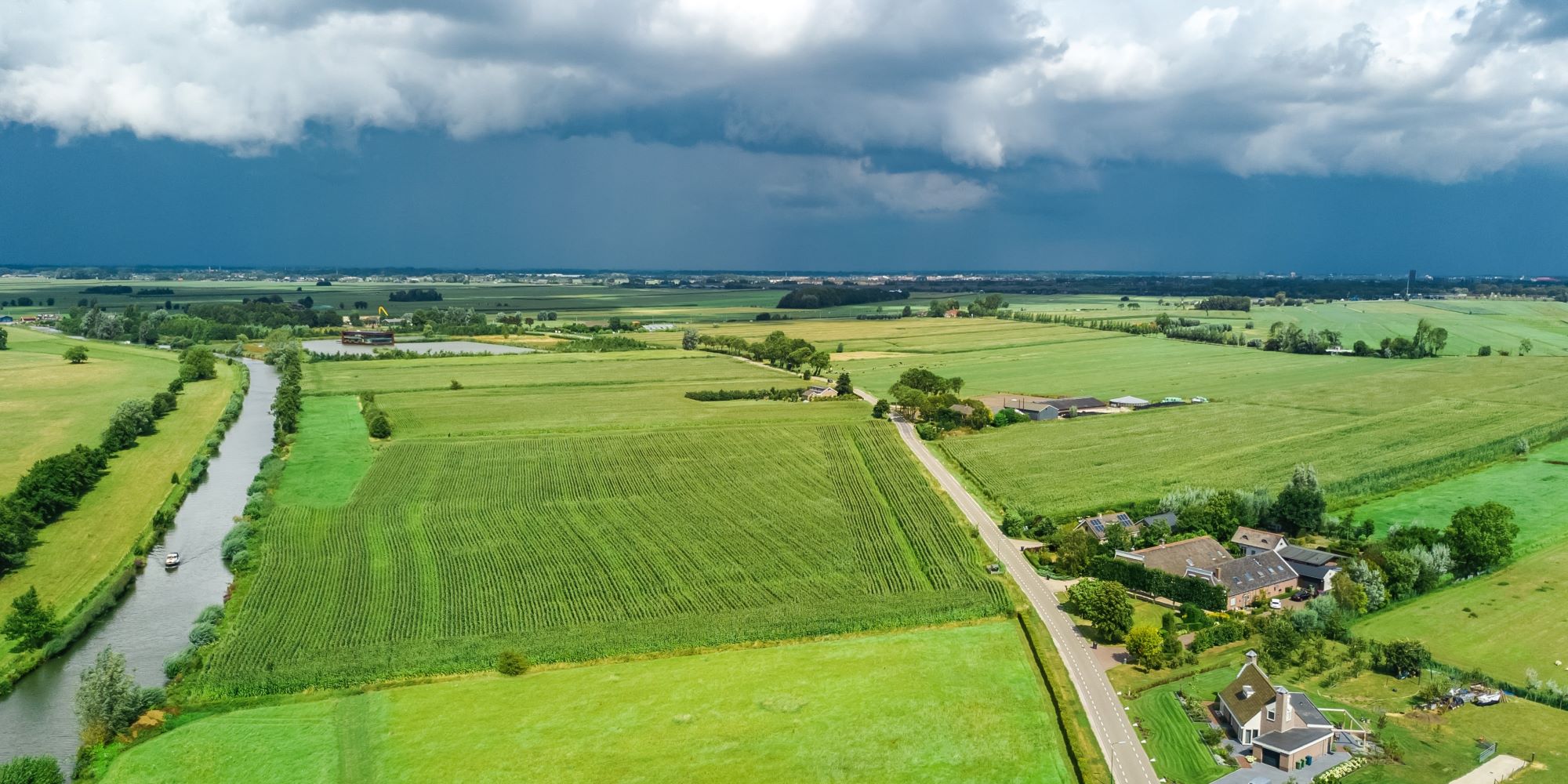 Landschap met veel weilanden en een donkere lucht